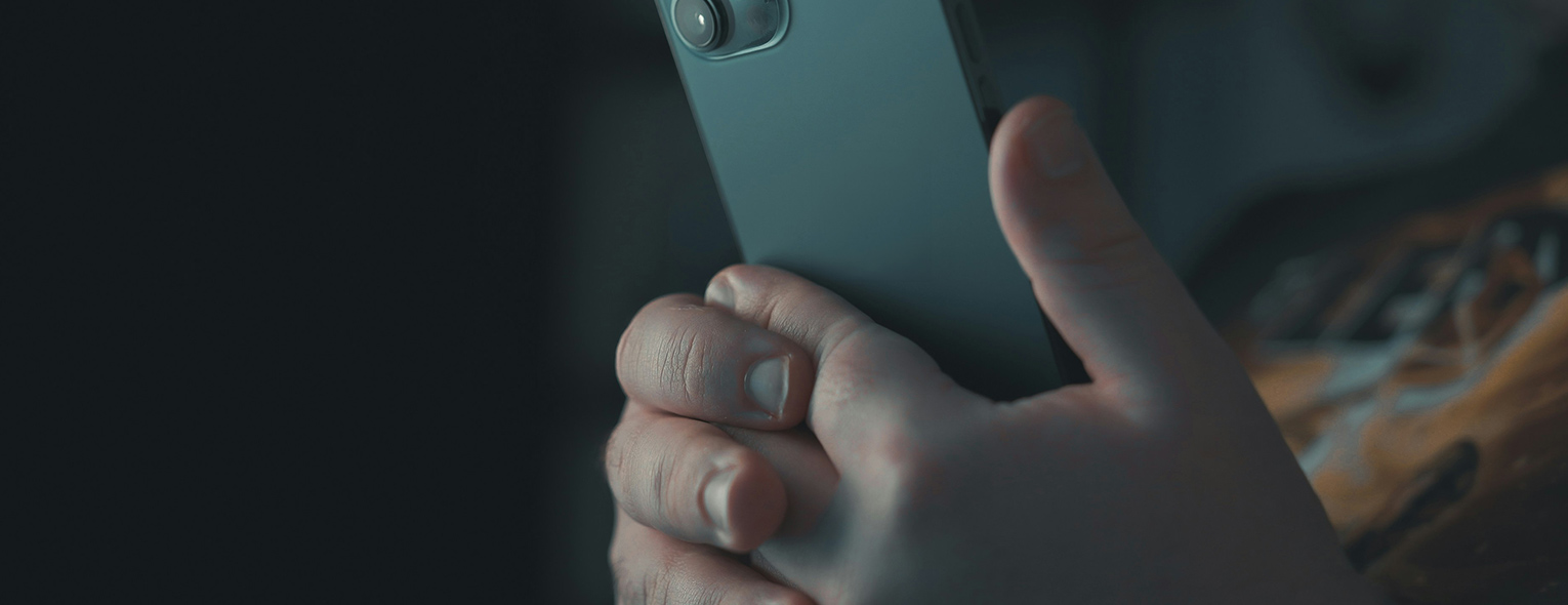 In einer Nahaufnahme sehen wir zwei Hände, die ein mint-farbenes Handy halten